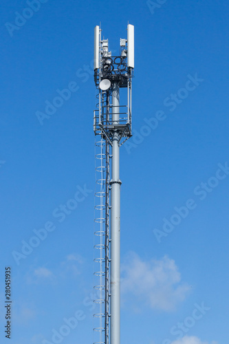 Gray pipe telecommunication tower on blue sky background, Vertical shot. photo