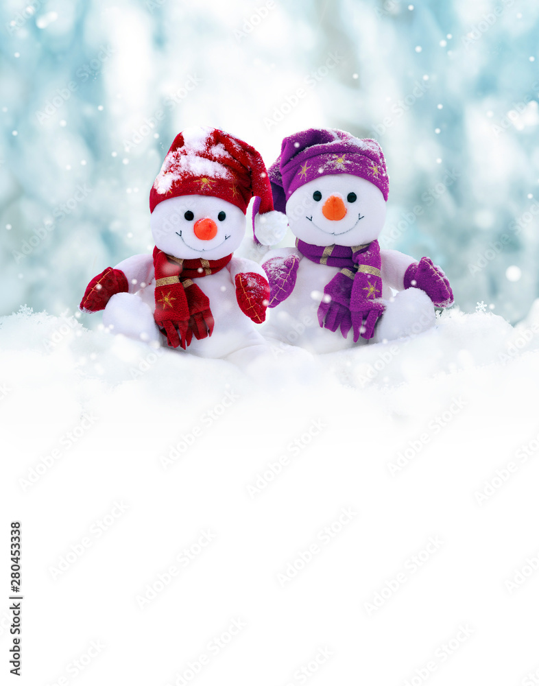 Two little snowmen the girl and the boy in caps and scarfs on snow in the winter. Background with a funny snowman. Christmas card.