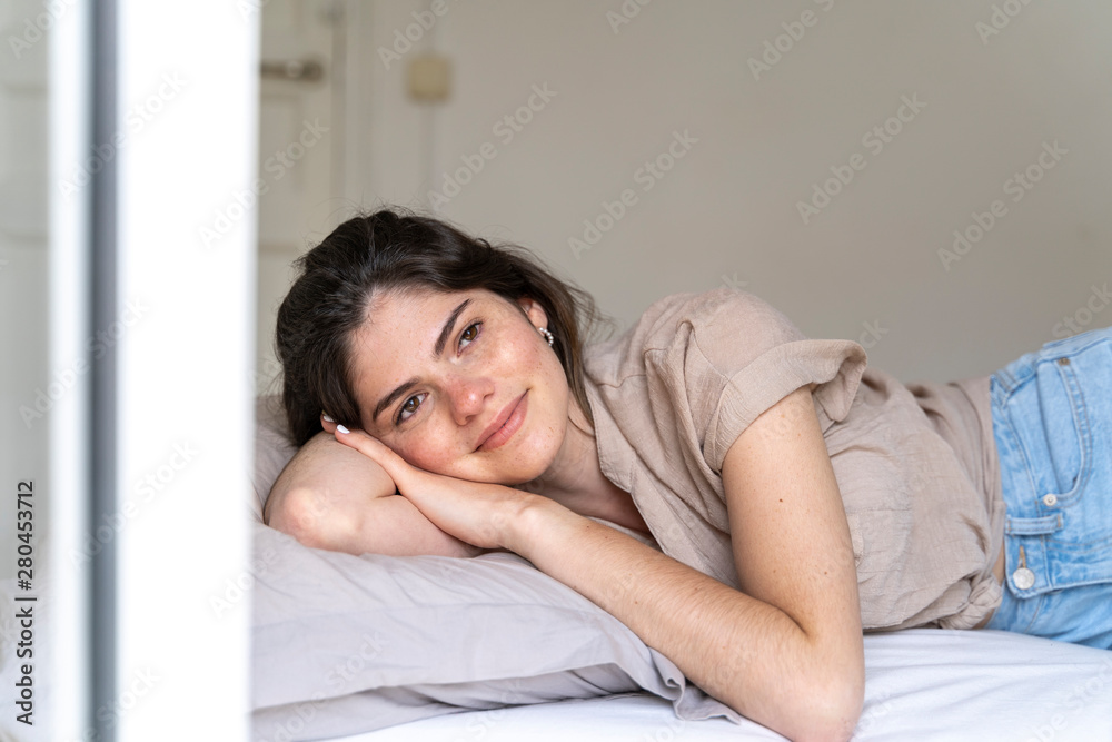 Smiling young woman lying on bed Smiling young woman lying on bed