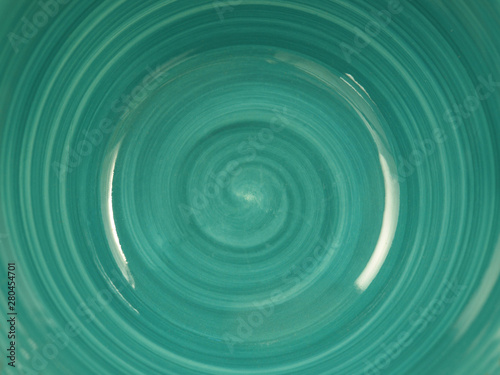  the bottom of a turquoise ceramic plate with a spiral pattern
