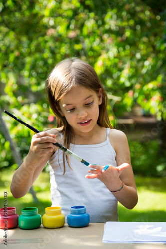 Girl in garden painting her hand with blue color photo