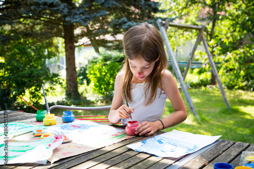 Little girl painting at table in the garden photo