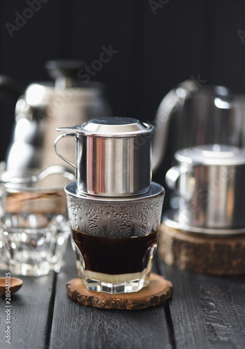 Making Vietnamese black drip coffee in phin on black background