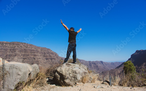 Man whit arm raised in the mountain on a sunny day, feeling of freedom.