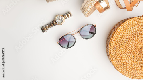 Wicker fashionable bag, sunglasses, and expensive watches Summer fashion, the concept of a holiday. On a white background