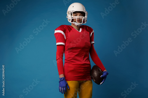 Image of american woman football player in white helmet, sportswear and ball in her hand