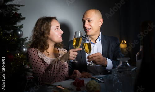 Happy couple drink champagne and watch TV on Christmas night