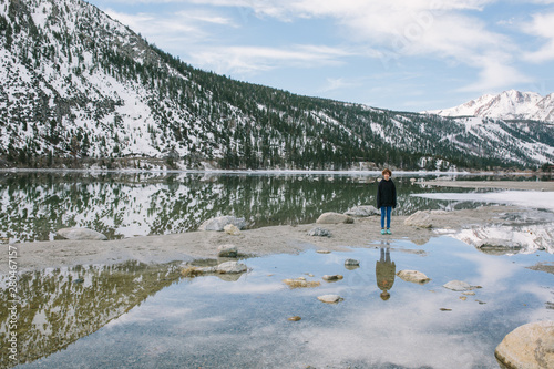 A girl stands by water of partially frozen June lake photo