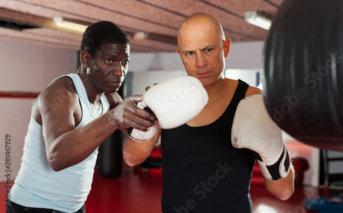African american trainer teaches man in boxing