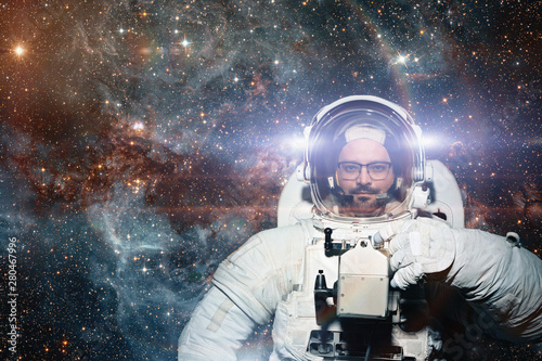 Fototapeta Naklejka Na Ścianę i Meble -  Astronaut in spaceman suit and helmet looks at camera at space background. People in space, exploration concept. Elements of this image furnished by NASA