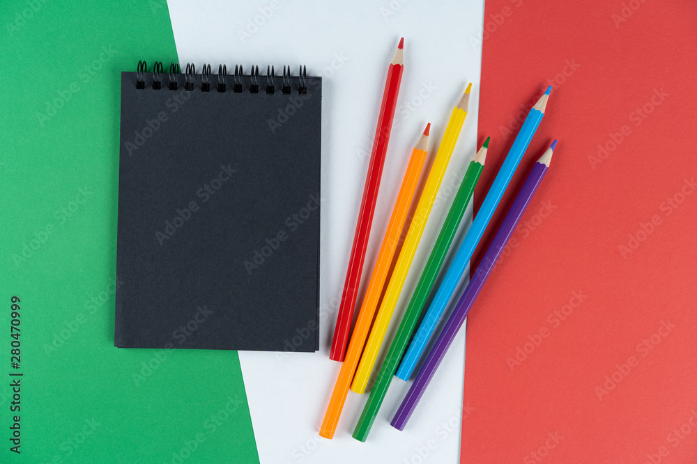 Blacklist Italy. Mourning, ban, sanctions, politics. black notebook and lgbt colored pencils lies on Italian flag. Mock up, copy space, pattern, cardboard texture. Blacklist Italy. Mourning, ban, sanctions, politics. black notebook and lgbt colored pencils lies on Italian flag. Mock up, copy space, pattern, cardboard texture.