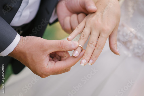 The groom puts on a finger ring wedding bride. Wedding registration of marriage. Close-up of the hands of the couple
