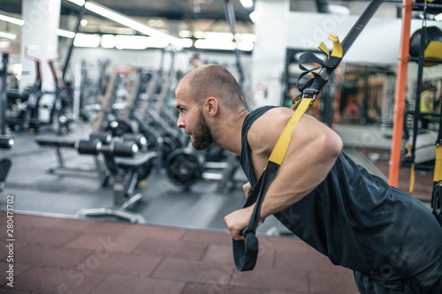 instructor at the gym doing Fitness man workout on the rings. Fitness man in the gym. Fitness style. Workout on rings. Sport and fitness. 