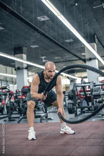 Man with battle rope battle ropes exercise in the fitness gym. 