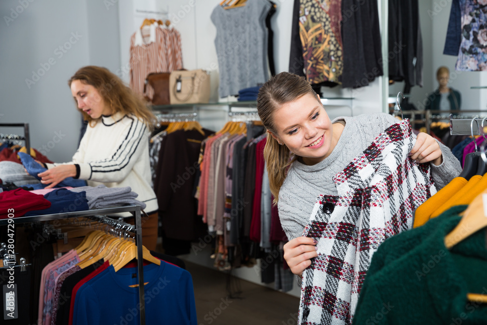 Obraz premium Clothing shop with women choosing overcoats