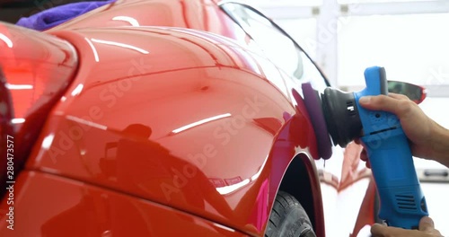 In the car center (in the garage), professionals polish a new sports car. Luxury car polishing. Concept of: Racing, Sport car, New, Slow motion, Nascar, Red, Chrome plated.