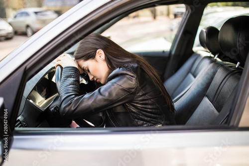 Young stressed or tired girl in car lying on steering wheel © dianagrytsku