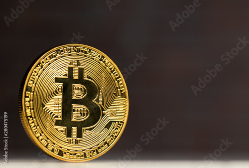 physical bitcoin standing at a white table in front of a brick wall