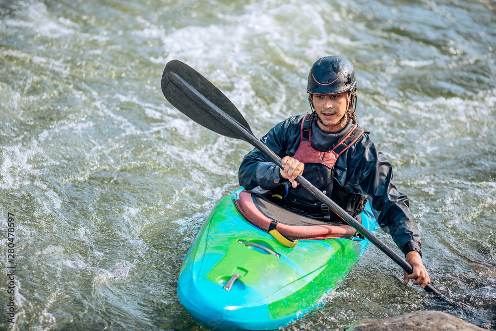 Obraz premium Whitewater kayaking, extreme sport rafting. Guy in kayak sails mountain river