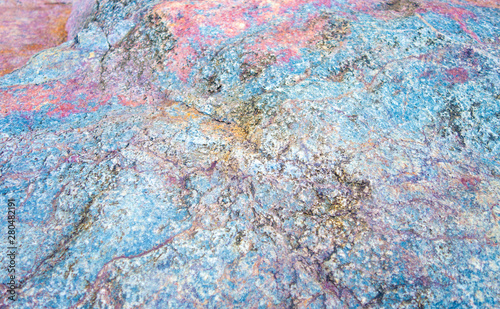 Colorful stone texture background. Big rock with colors of rainbow close up. Top view.