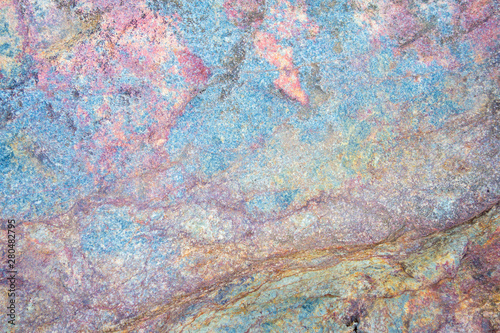 Colorful stone texture background. Big rock with colors of rainbow close up. Top view.