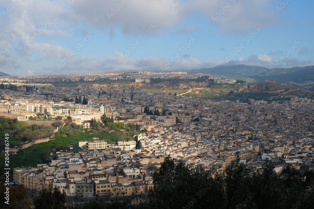 high angle view of Fez, one of four Imperial cities of Morocco. Dense houses cityscape under sunlight cloudy blue sky