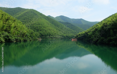 green mountains and symetrical reflection in peaceful lake. blue sunny sky and white cloud. South Hill Bamboo Sea in China Jiangsu. wide angle