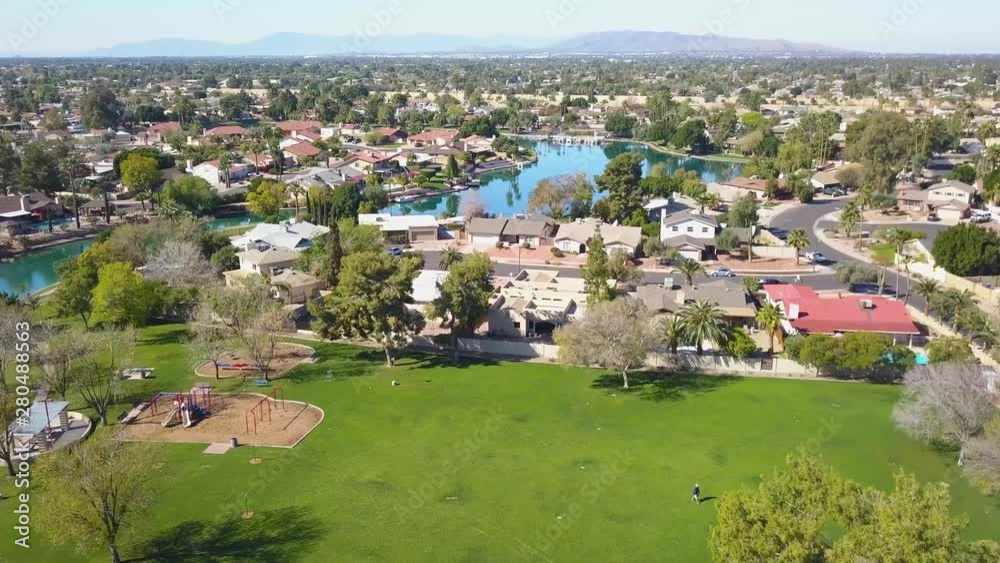 aerial view flying across a park, over homes up to a lake Stock Video ...