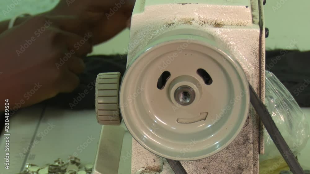 Close-up of African hands turning the volant of an old sewing machine in a garment workshop