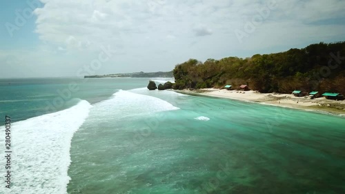 Establishing Drone shot flying along the coastline of Padang Padang beach in Bali, Indonesia while waves roll in below. photo