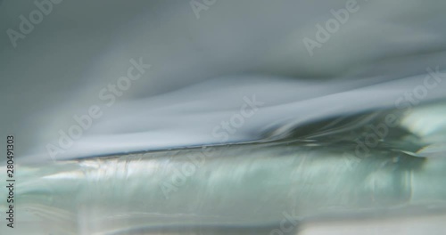 Transparent fluid moving slowly towards the camera, building waves. Static macro shot. photo