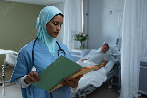 Female doctor in hijab looking at medical report in the ward photo