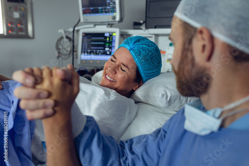 Man comforting pregnant woman during labor in operating room photo