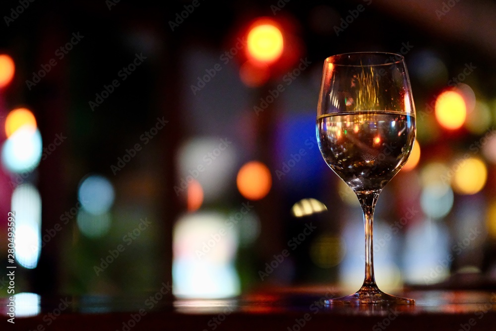 Close up a glass of wine on table. Blurred colorful lights background. Low angle. Bar and restaurant concept Close up a glass of wine on table. Blurred colorful lights background. Low angle. Bar and restaurant concept