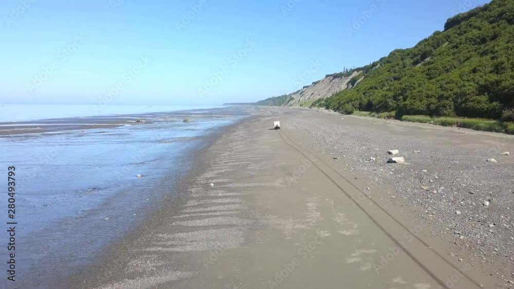 Aerial, drone shot, following a 4x4 overland RV, driving on a beach, at low tide, in Deep Creek State Recreation Area, Ninilchik, Alaska, USA Aerial, drone shot, following a 4x4 overland RV, driving on a beach, at low tide, in Deep Creek State Recreation Area, Ninilchik, Alaska, USA
