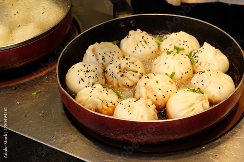 Canvas Print close up white fried buns in a rounded pan under light on cooking bench