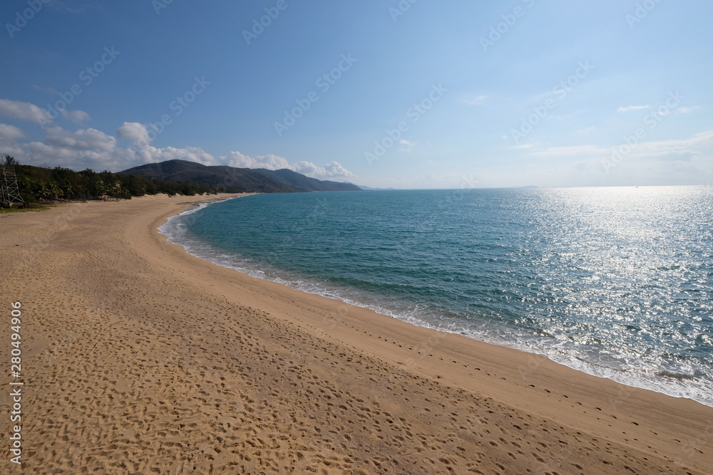 extended empty sand beach and coastline. nobody. sunny blue sky white cloud. blue sea with sunshine reflection. wide angle