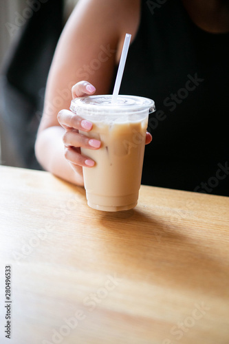 Wallpaper Mural Woman holding Iced Chai Latte in To Go Cup on Table, Coffee on Wooden Bar in Cafe, Close up photo Torontodigital.ca