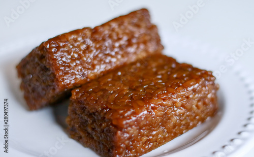 Wajik or wajid on white background.  Wajik is traditional snack made with steamed glutinous (sticky) rice and further cooked in palm sugar, coconut milk, and pandan leaves. photo