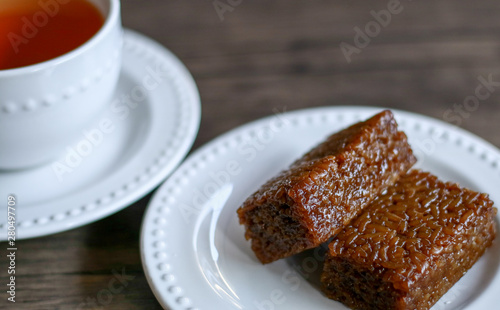 Wajik and a cup of tea on wood background.  Wajik is traditional snack made with steamed glutinous  sticky  rice and further cooked in palm sugar  coconut milk  and pandan leaves.
