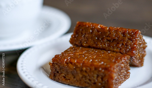 Wajik and a cup of tea on wood background.  Wajik is traditional snack made with steamed glutinous (sticky) rice and further cooked in palm sugar, coconut milk, and pandan leaves. photo