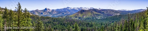 Panoramic view of wilderness areas in Yosemite National Park with evergreen forests covering valleys and snow capped mountains visible in the background  Sierra Nevada mountains, California © Sundry Photography