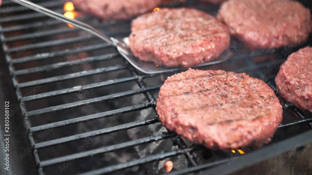 Lid opening on grill and spatula flipping alternative meat (Beyond Meat) burger patties on a barbecue, close up shot with flame in slow motion 4k. Lid opening on grill and spatula flipping alternative meat (Beyond Meat) burger patties on a barbecue, close up shot with flame in slow motion 4k.