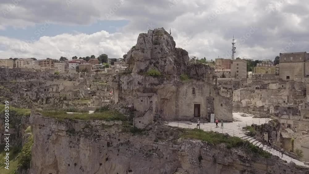 Aerial view of Matera in Italy. Camera moves towards Rock-hewn church. Cloudy sky. Aerial view of Matera in Italy. Camera moves towards Rock-hewn church. Cloudy sky.
