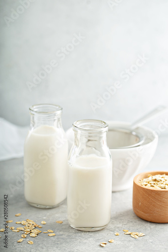 Homemeade oat milk in glass bottles with a sieve photo