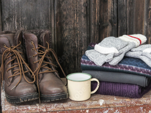 A horizontal photo of boots, scarfs and atin cup. photo