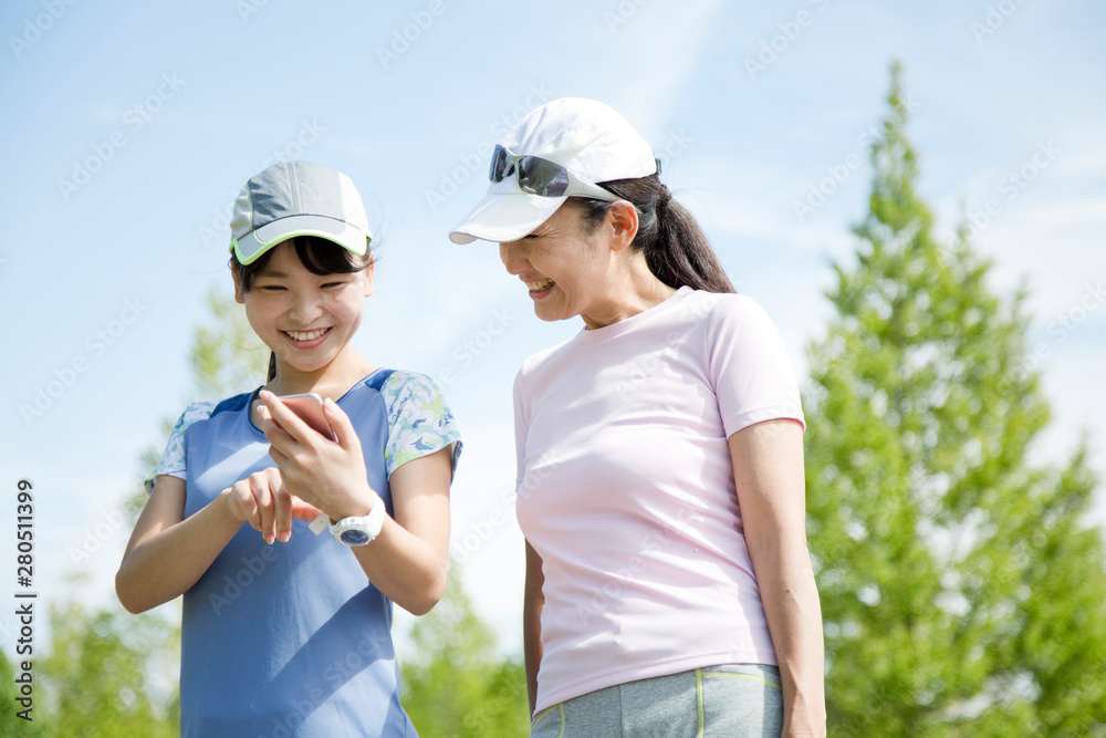 運動中にスマートフォンを見る親子 運動中にスマートフォンを見る親子