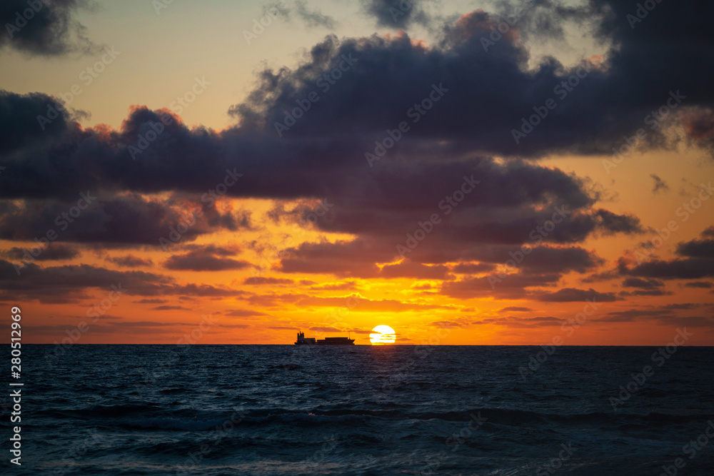 Silhouette of a fishing ship in the sea at early morning with the sun coming up in a summer sunny day, Florida, USA. Sunsert at South Beach, Miami.