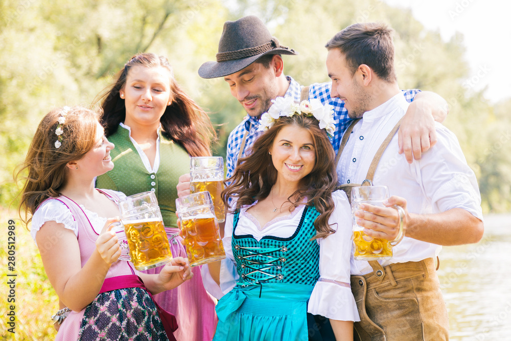 Freunde in bayerischen Tracht feiern an der Isar und trinken Bier. Oktoberfest München Freunde in bayerischen Tracht feiern an der Isar und trinken Bier. Oktoberfest München