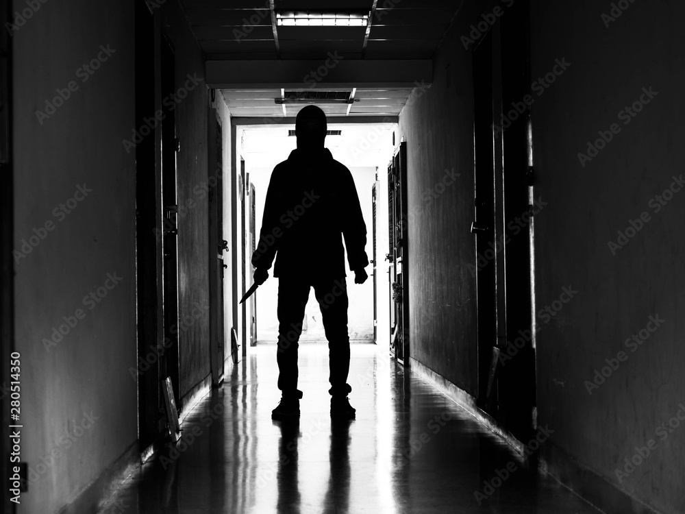 Man silhouette walking away with knife in the light of opening door in dark room, Threat Concept. Man silhouette walking away with knife in the light of opening door in dark room, Threat Concept.
